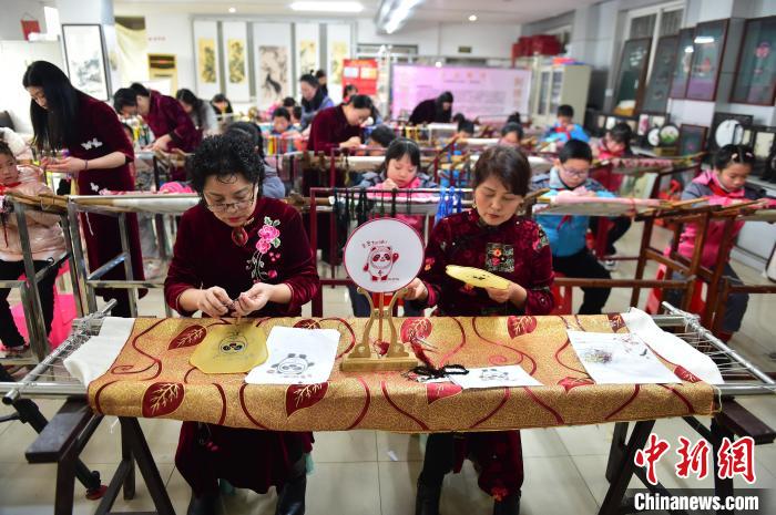 江西省級(jí)非遺豫章繡傳承人手把手指導(dǎo)小學(xué)生繡制2022年北京冬奧會(huì)吉祥物“冰墩墩”形象。　喻云亮 攝