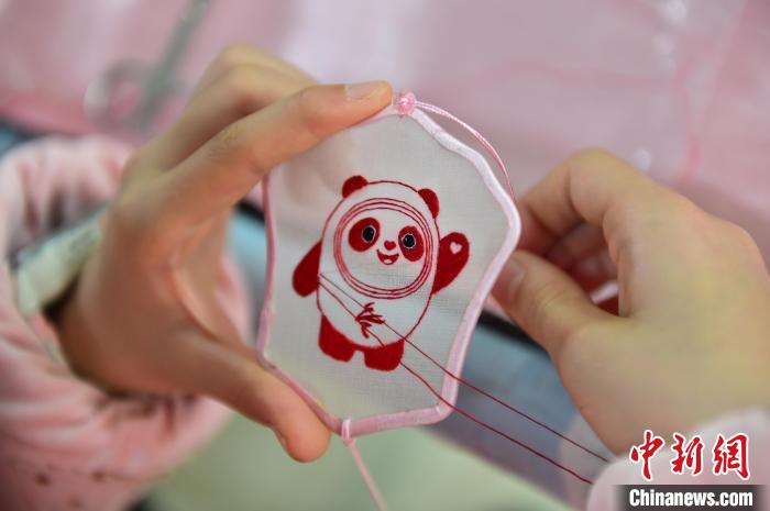 圖為一名小學(xué)生正在繡制2022年北京冬奧會(huì)吉祥物“冰墩墩”形象?！∮髟屏?攝