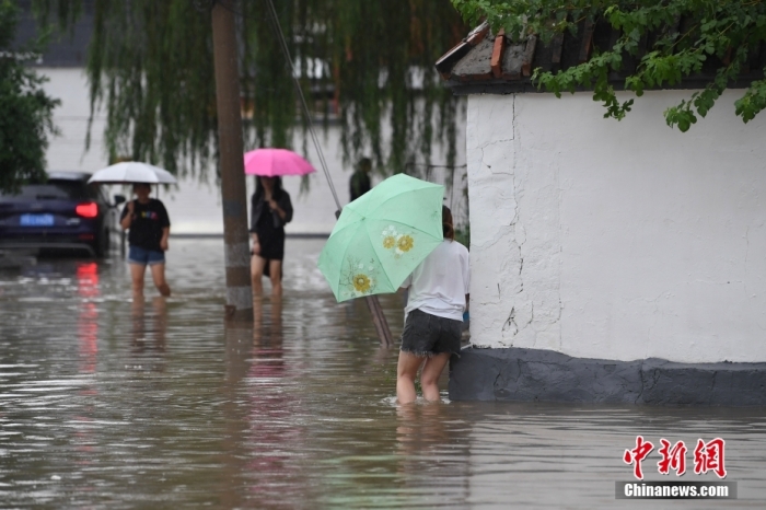 7月31日，市民行走在雨中的北京房山區(qū)瓦窯頭村。北京市氣象臺當(dāng)日10時發(fā)布分區(qū)域暴雨紅色預(yù)警信號。北京市水文總站發(fā)布洪水紅色預(yù)警，預(yù)計當(dāng)日12時至14時，房山區(qū)大石河流域?qū)⒊霈F(xiàn)紅色預(yù)警標(biāo)準(zhǔn)洪水。<a target='_blank' href='/'><p  align=