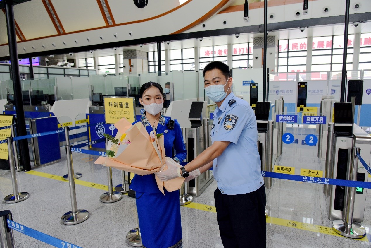 磨憨出入境邊防檢查站民警為中老鐵路第100萬(wàn)名出入境旅客，D888次國(guó)際旅客列車(chē)?yán)蠐爰藙?wù)員森達(dá)拉·妮緹婭（Sengdala Nitiya），送上鮮花。黃遠(yuǎn)飛 攝