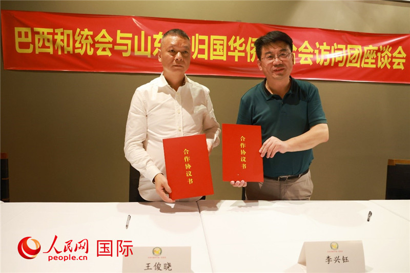 中國(guó)僑聯(lián)副主席、山東省僑聯(lián)主席李興鈺（右）與巴西和統(tǒng)會(huì)會(huì)長(zhǎng)王俊曉簽署合作協(xié)議書。人民網(wǎng)記者 陳海琪攝