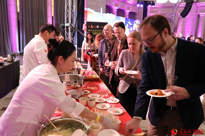 當地時間3月7日晚，華盛頓聯(lián)合車站廣場舉行駐美使團“使館主廚挑戰(zhàn)賽”。圖為當地民眾在中國展臺前體驗中國美食。人民網記者 李志偉攝