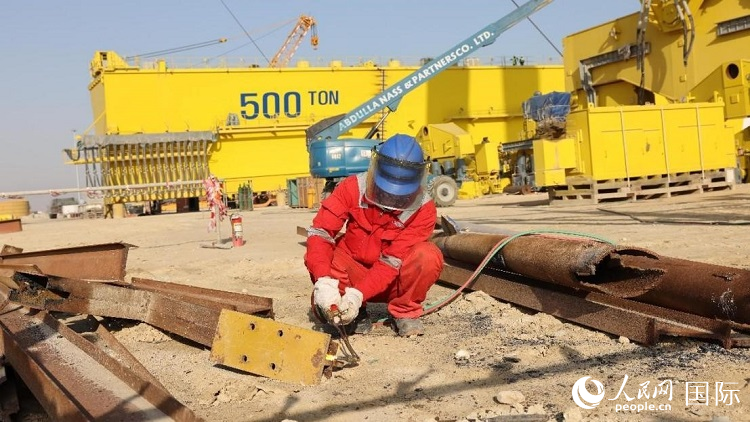 工人正在龍門吊吊裝現(xiàn)場切割金屬件。人民網(wǎng)記者管克江攝