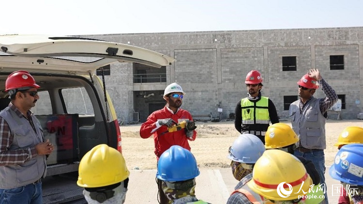 穆薩瓦爾(圖中紅衣人）現(xiàn)場演示工具操作規(guī)范。人民網(wǎng)記者 管克江攝