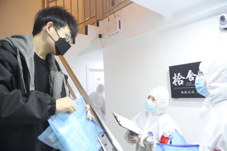 社區(qū)工作人員和志愿者身穿防護(hù)服上門送馬應(yīng)龍大健康防疫包。徐帥攝