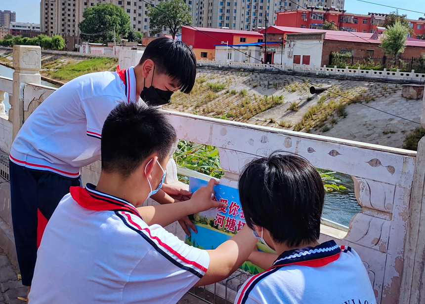徐水小學(xué)學(xué)雷鋒志愿者在瀑河河邊張貼防溺水警示標(biāo)語(yǔ)。 徐水區(qū)委宣傳部供圖
