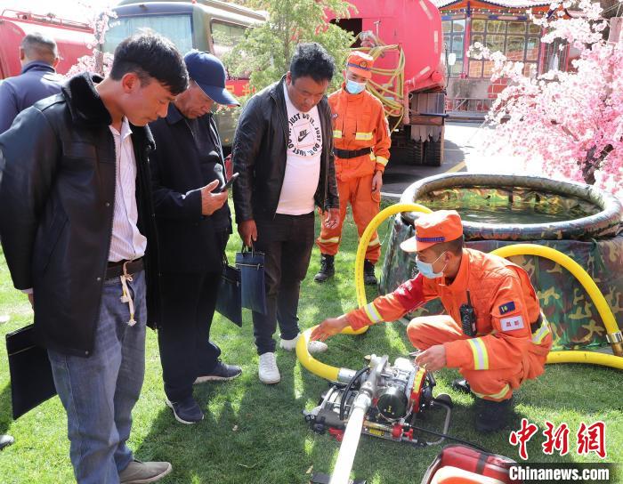 圖為森林消防員為護(hù)林員講解滅火裝備的使用方法?！〔际猩窒乐ш?duì) 供圖