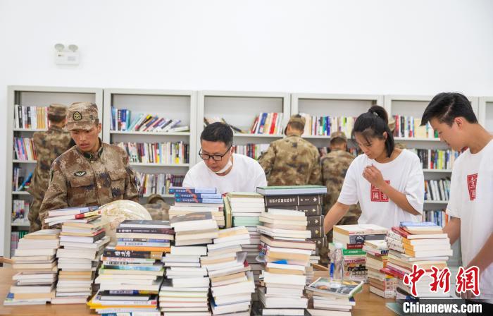 圖為志愿者們和邊防戰(zhàn)士整理圖書?！詵| 攝