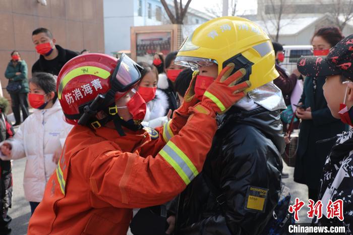 圖為小朋友體驗(yàn)試穿消防滅火防護(hù)服。　楊龍建 攝