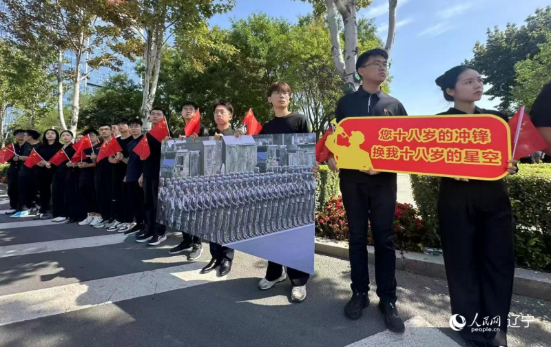 沈陽市人民廣場上，大學生們手持閱兵的圖片，告慰英烈。人民網記者 周頌雪攝