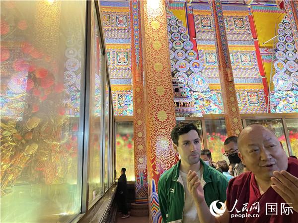 7月25日，省級(jí)非物質(zhì)文化遺產(chǎn)項(xiàng)目塔爾寺酥油花的代表性傳承人朋措堅(jiān)參（右）在塔爾寺酥油花館講解酥油花的制作過程。人民網(wǎng) 謝瑩攝