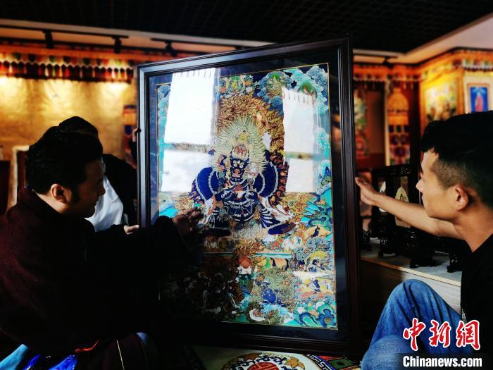 圖為久美尖措(左)與徒弟們展示唐卡作品?！?zhí)砀?攝