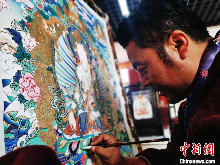 圖為久美尖措創(chuàng)作唐卡?！?zhí)砀?攝