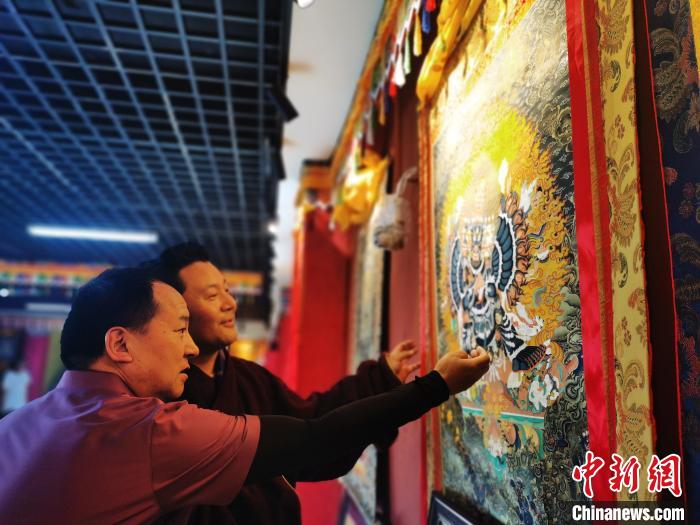 圖為久美尖措展示唐卡作品?！?zhí)砀?攝