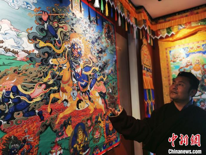圖為久美尖措展示唐卡作品?！?zhí)砀?攝