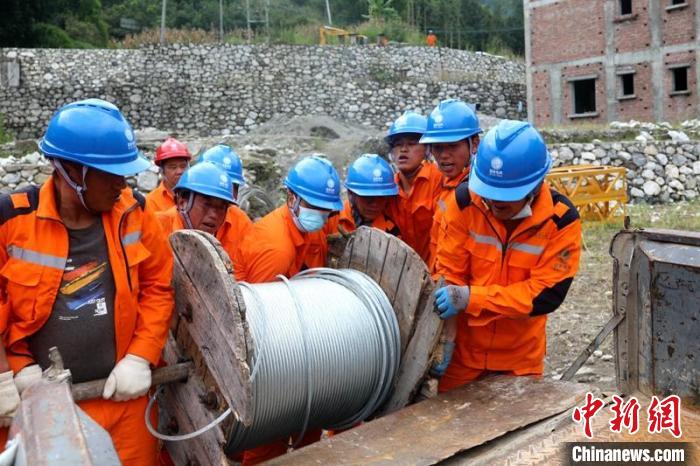 國網(wǎng)四川送變電公司搶險隊員將重達370公斤的鋼絞線搬上車?！⑾驸C 攝