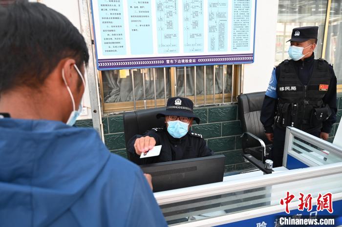圖為移民管理警察登記完身份信息后將證件歸還給行人?！≮w朗 攝