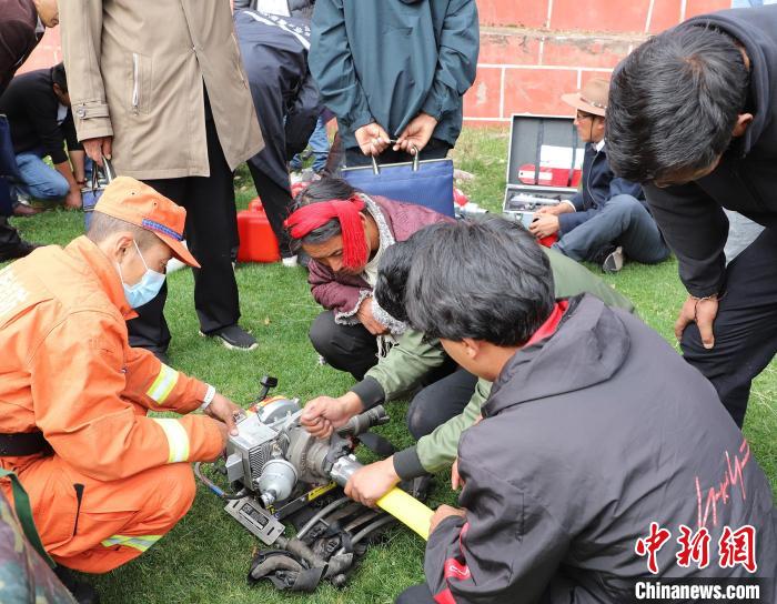 圖為森林消防員為護(hù)林員講解滅火裝備的使用方法?！〔际猩窒乐ш?duì) 供圖