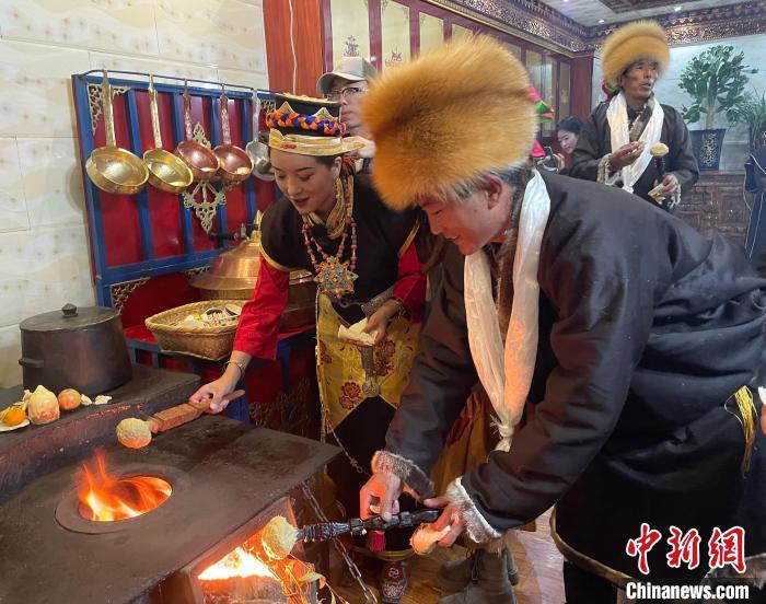 圖為人們在火上烤節(jié)日美食“結(jié)達”?！∪轿木?攝