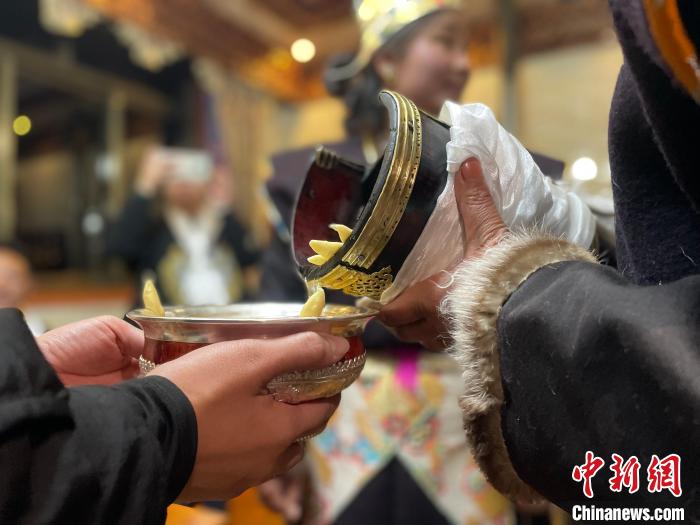 圖為主人在碗中斟滿青稞酒?！∪轿木?攝