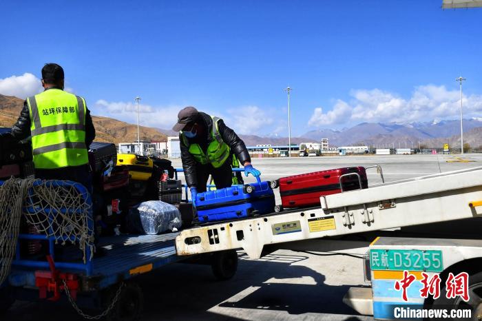 圖為機(jī)場(chǎng)工作人員傳送旅客行李箱。　周航 攝
