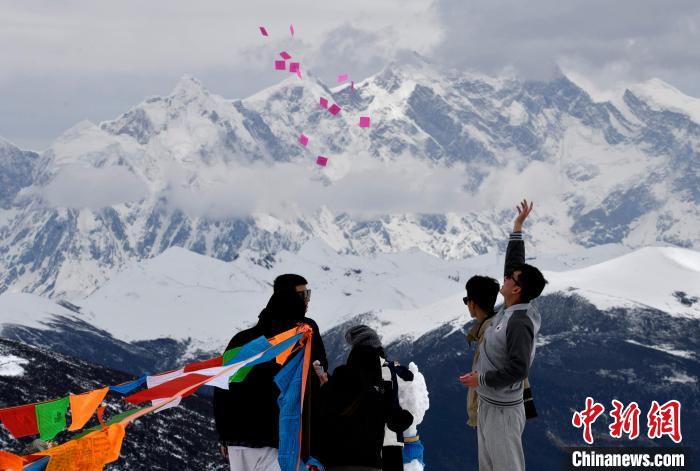 圖為5月14日，游客在西藏林芝色季拉山觀景臺拋灑“隆達”(風馬旗，藏族民眾的一種祈福方式)?！±盍?攝