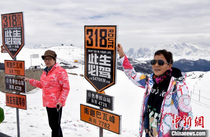 圖為5月14日，西藏林芝色季拉山觀景臺，游客與南迦巴瓦峰合影。　李林 攝