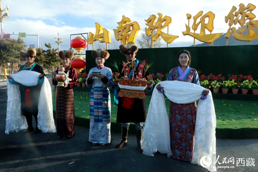 扎西曲登社區(qū)的居民在“山南歡迎您”標(biāo)志前，手持潔白哈達(dá)和切瑪，列隊(duì)迎接來(lái)自區(qū)內(nèi)外的游客，用最隆重的禮儀開(kāi)啟一場(chǎng)沉浸式藏歷新年民俗體驗(yàn)之旅。人民網(wǎng)記者 吳雨仁攝