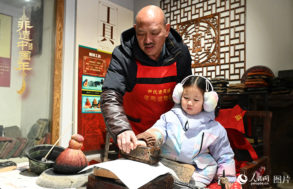 2025年1月27日，河南開封朱仙鎮(zhèn)木版年畫藝人尹國法指導(dǎo)小朋友研習(xí)年畫印制技藝。朱仙鎮(zhèn)木版年畫源自漢唐壁畫藝術(shù)，是中國木版年畫的鼻祖。2006年5月20日，朱仙鎮(zhèn)木版年畫經(jīng)國務(wù)院批準(zhǔn)列入第一批國家級非物質(zhì)文化遺產(chǎn)名錄。人民網(wǎng)記者 王玉興攝