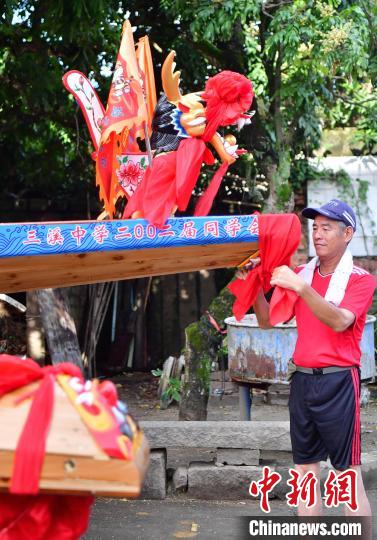 圖為5月29日，長樂江田鎮(zhèn)村民為即將入水的新龍舟系紅布。　張斌 攝