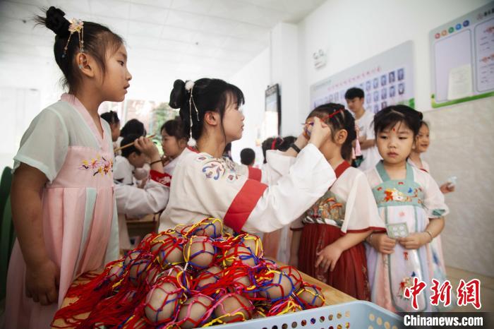 圖為幼兒園的老師們穿上漢服為小朋友們戴上彩蛋，寓意著幸福安康?！《^生 攝